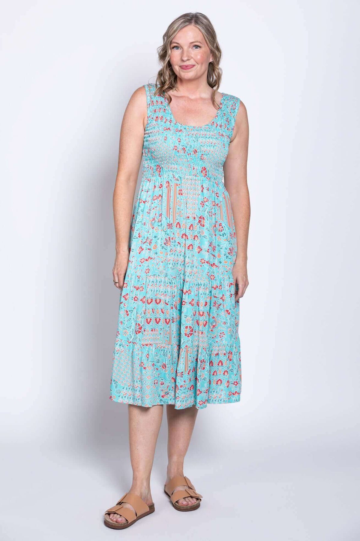 Woman in blue sleeveless dress with red flowers, angled front view