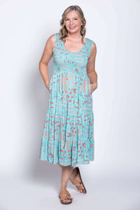 Woman wearing a light blue sleeveless tiered dress with red floral print, front angled view