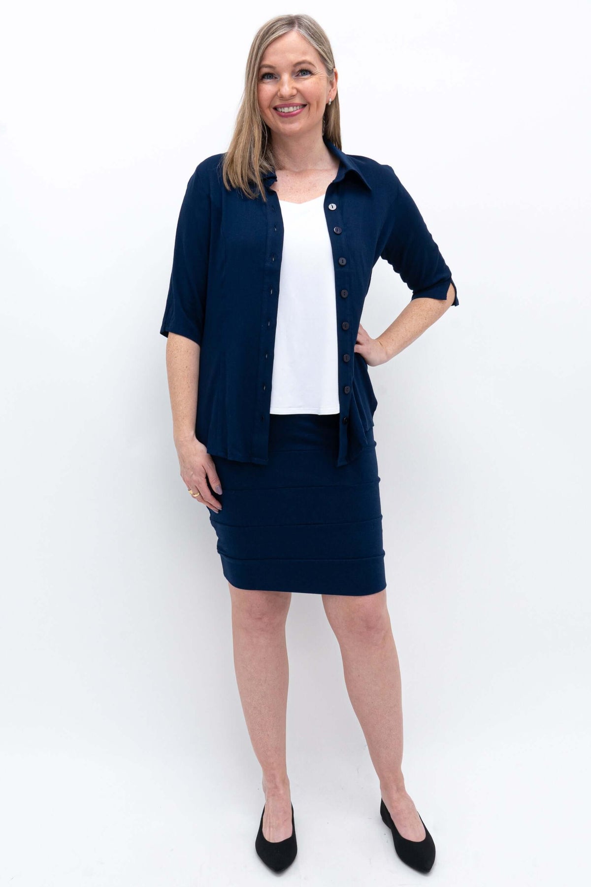Woman posing in navy stretch pencil skirt and navy shirt, front angle