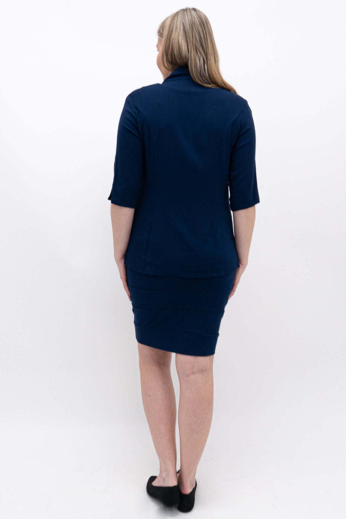 Woman showing the back view of a navy pencil skirt and matching shirt