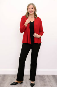 Front view of woman wearing a red cardigan, black top, and black pants on a white background