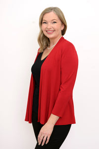 Side view of woman wearing a red cardigan, black top, and black pants on a white background