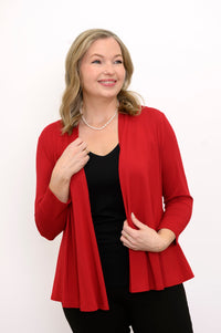 Front view of woman wearing a red cardigan, black top, and black pants on a white background