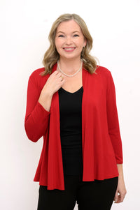 Front view of woman wearing a red cardigan, black top, and black pants on a white background