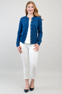 Woman modeling a blue crewneck knit cardigan styled over a white crop top and white trousers.