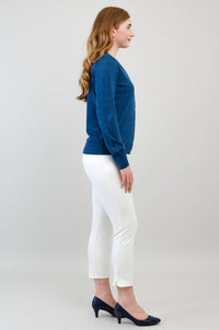 Full length shot of a woman wearing a blue merino wool button up cardigan layered with white pants