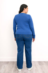 Back view of a pacific blue raglan sweater, showcasing a seamless rear panel, long sleeves, and dark denim jeans.