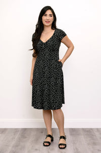 Woman posing with her hand in the pocket of the polka dot printed dress she is wearing