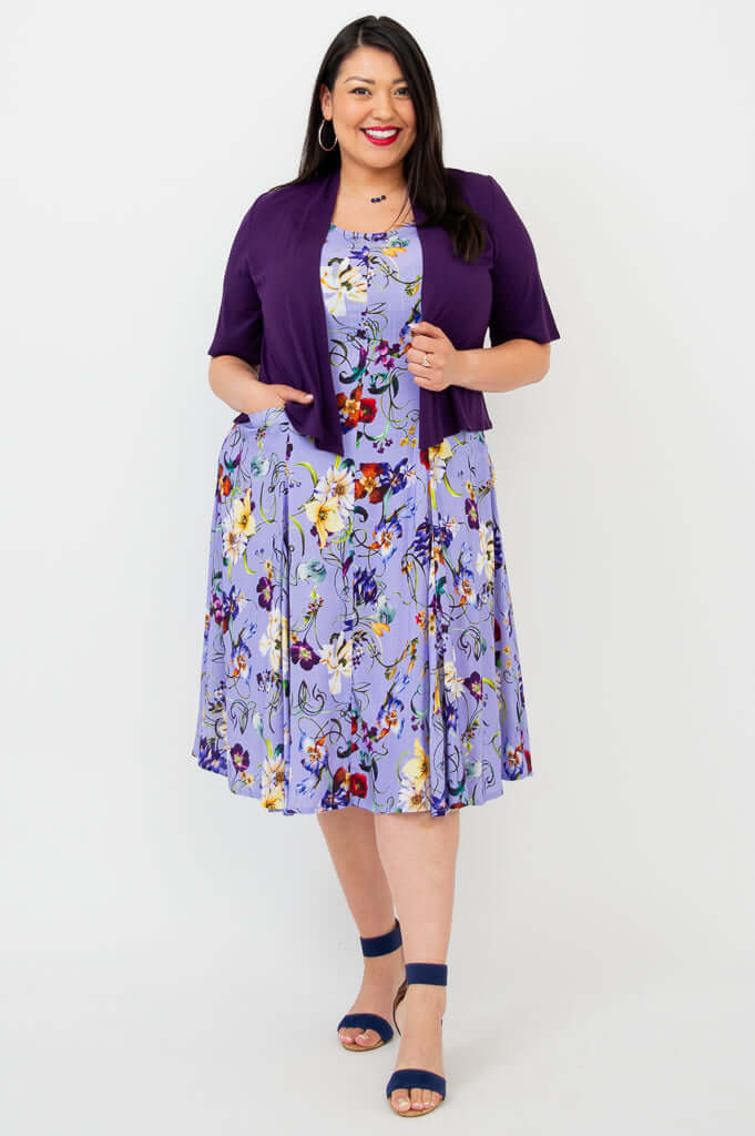 Woman layered in a purple short-sleeve cardigan over a lilac floral A-line dress