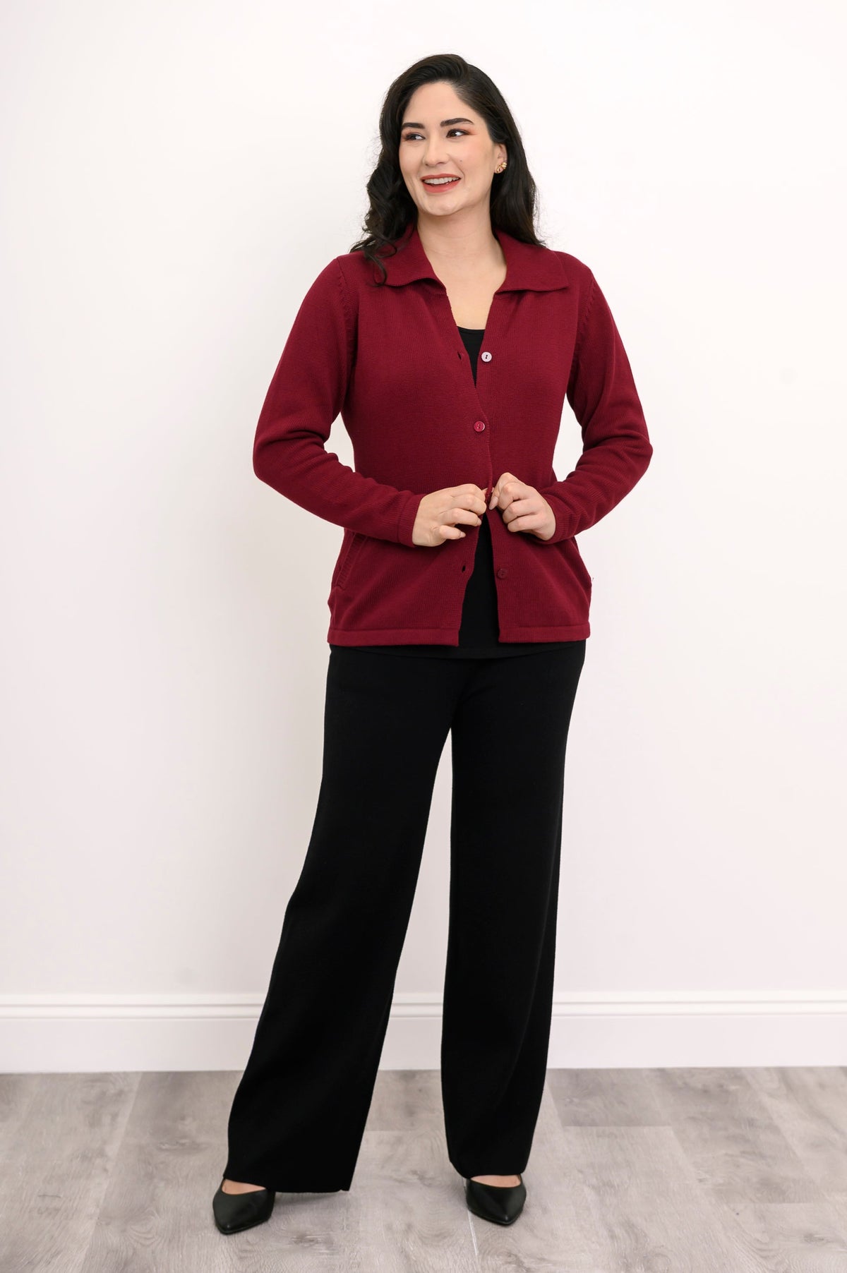 Hip-length deep red button-down sweater styled with casual black trousers for a clean, modern look.