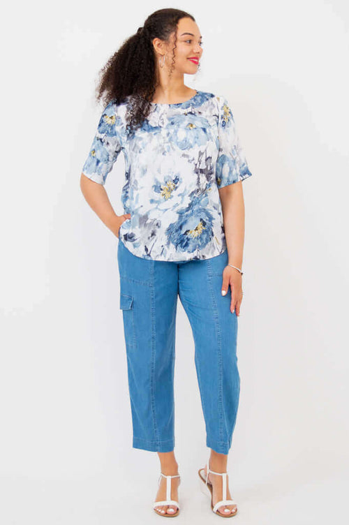 Full body view of model in Liza bamboo-linen blouse and blue pants, standing with hands in pockets