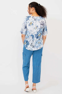 Back view of model wearing Liza bamboo-linen blouse with curved hem and blue floral pattern
