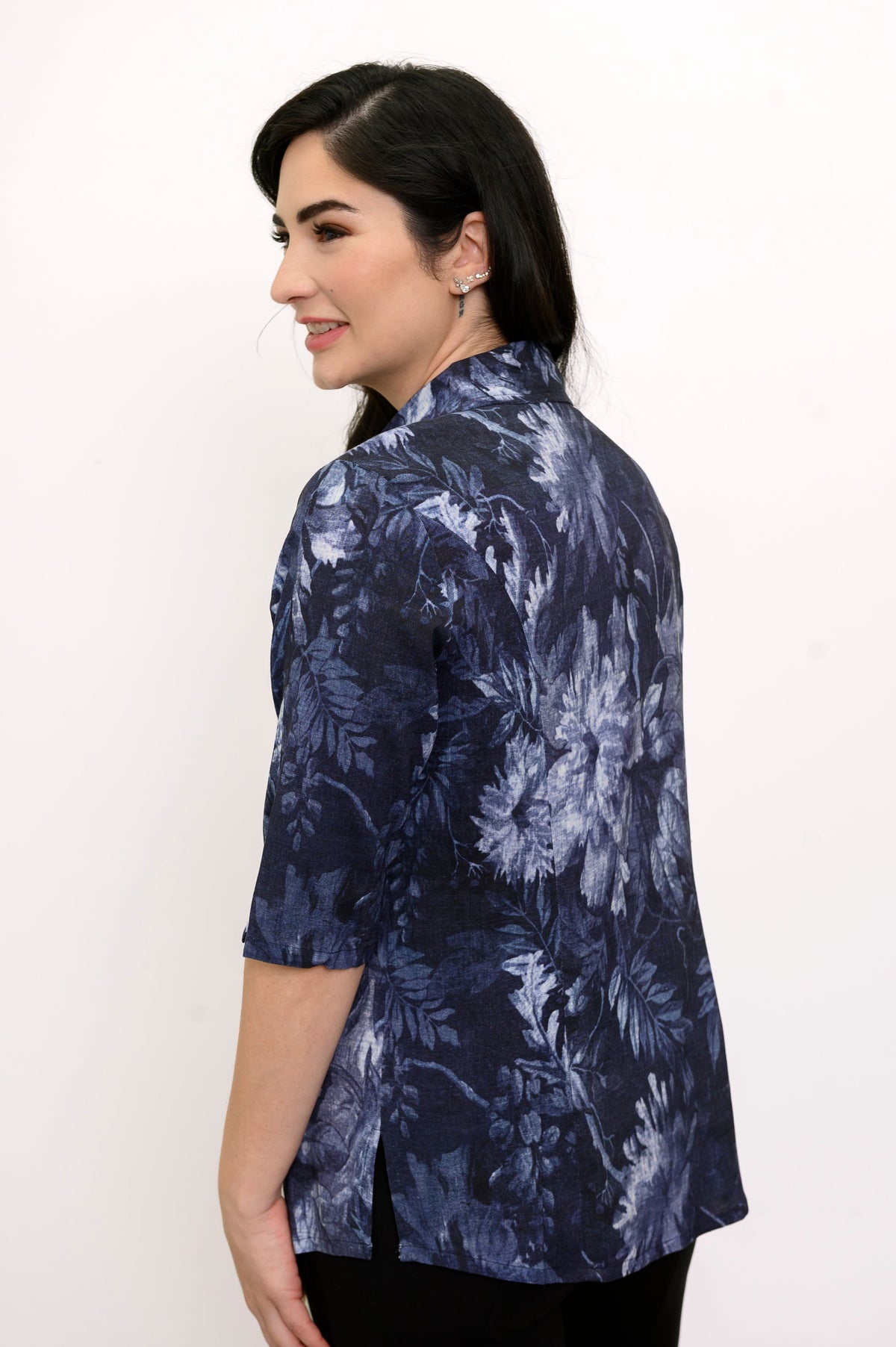 Woman facing away and smiling while wearing a dark blue floral blouse