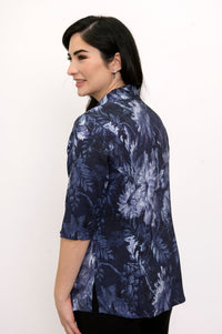 Woman facing away and smiling while wearing a dark blue floral blouse