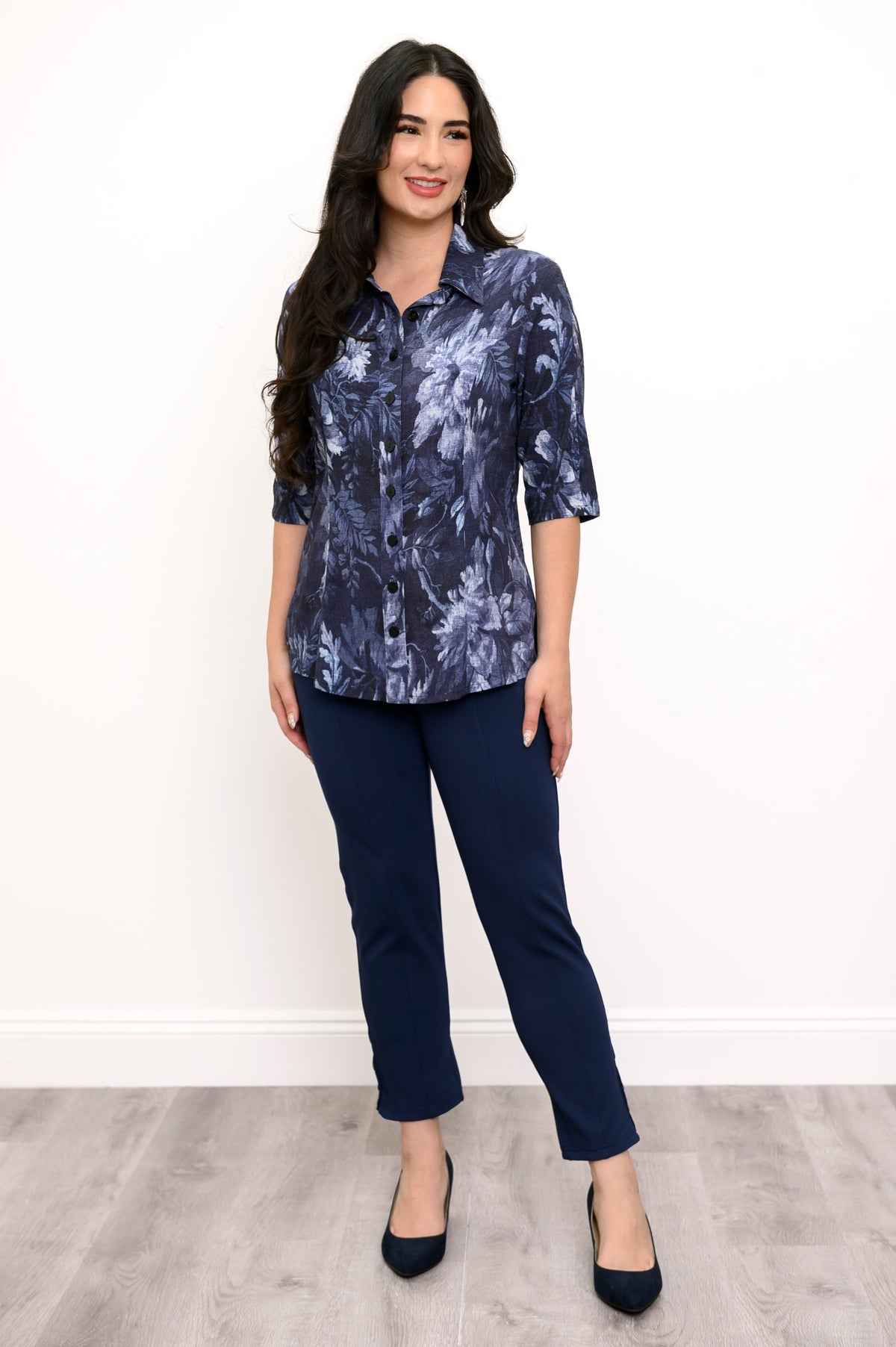 Full body front view of woman modeling dark blue floral print top and navy blue pants