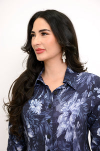 Close up view of model facing slightly left while wearing silver earrings and a navy blue floral blouse