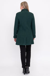 Woman wearing a green coat, black pants, and black shoes on a white background, back view