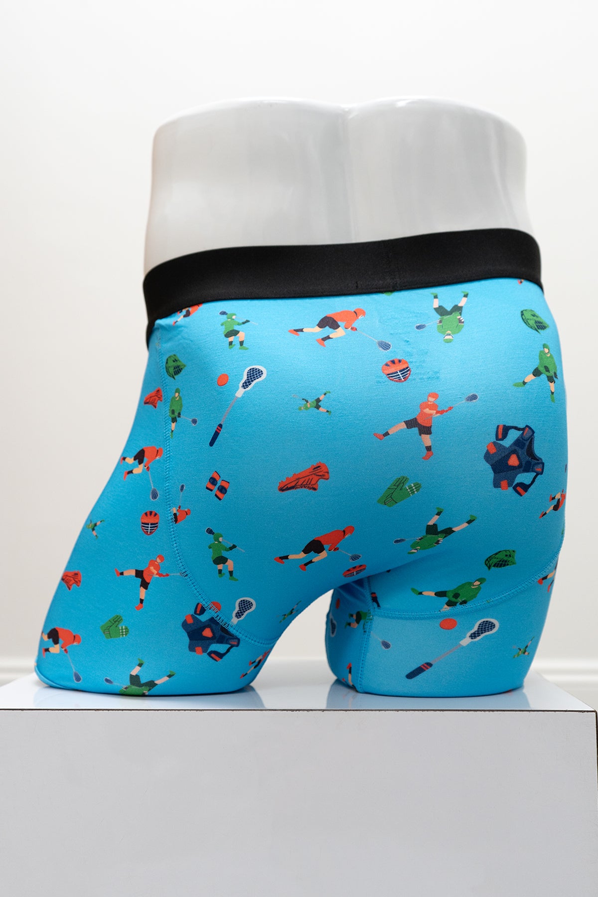 Blue boxer briefs with a colorful lacross pattern on a mannequin against a white background, back view