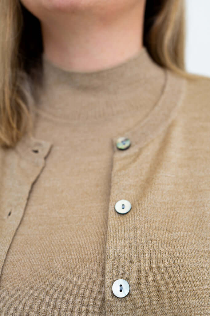 Macro shot of tan Merino wool cardigan showing textured buttons and knit detail