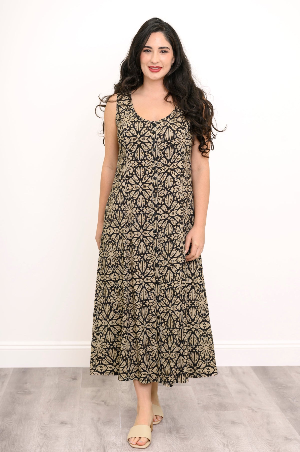 Full body shot of woman wearing black and beige patterned maxi dress against a white background
