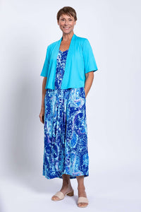 Woman in blue printed maxi dress with pockets and turquoise cardigan smiling