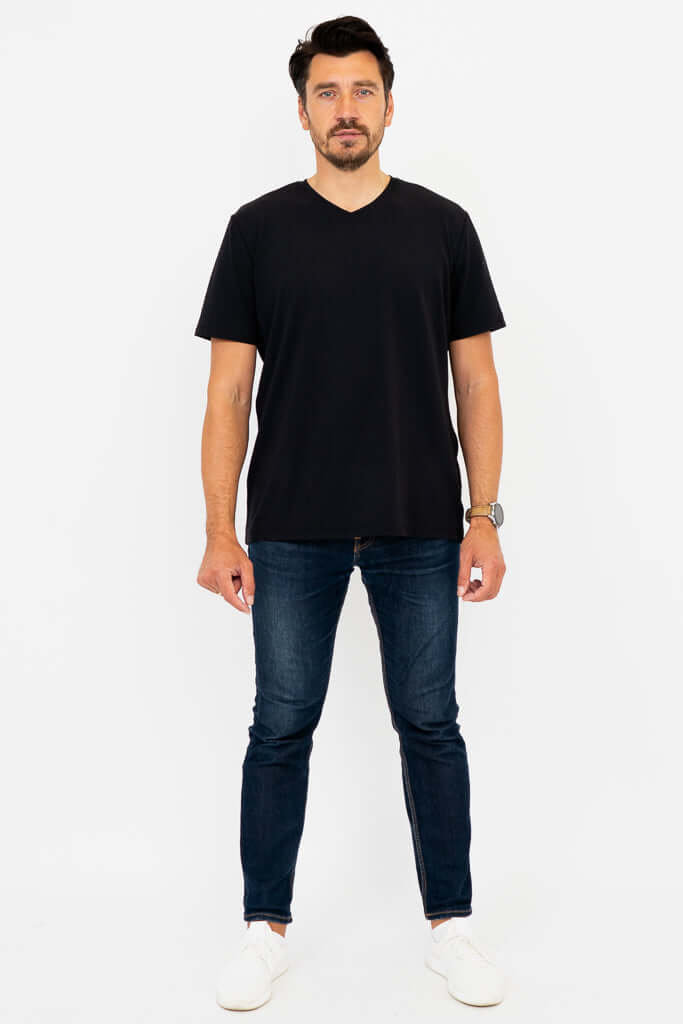 Man in black high V-neck t-shirt and jeans, standing straight, full body front view