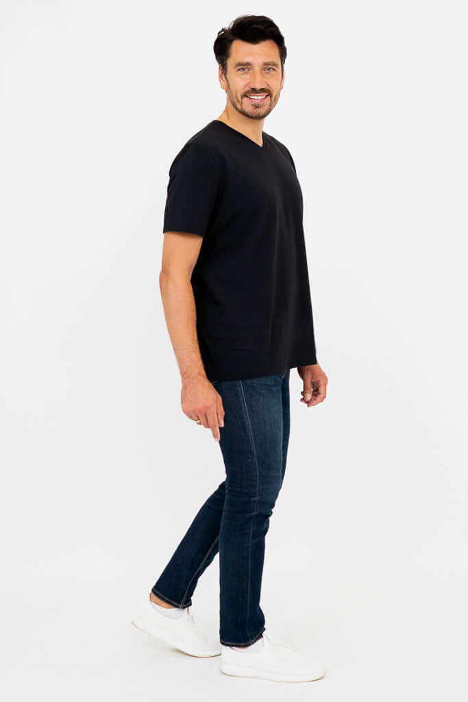 Man in black high V-neck t-shirt, side view, walking with a smile