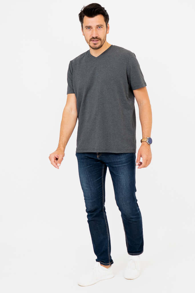 Man standing in dark grey V-neck T-shirt and blue jeans