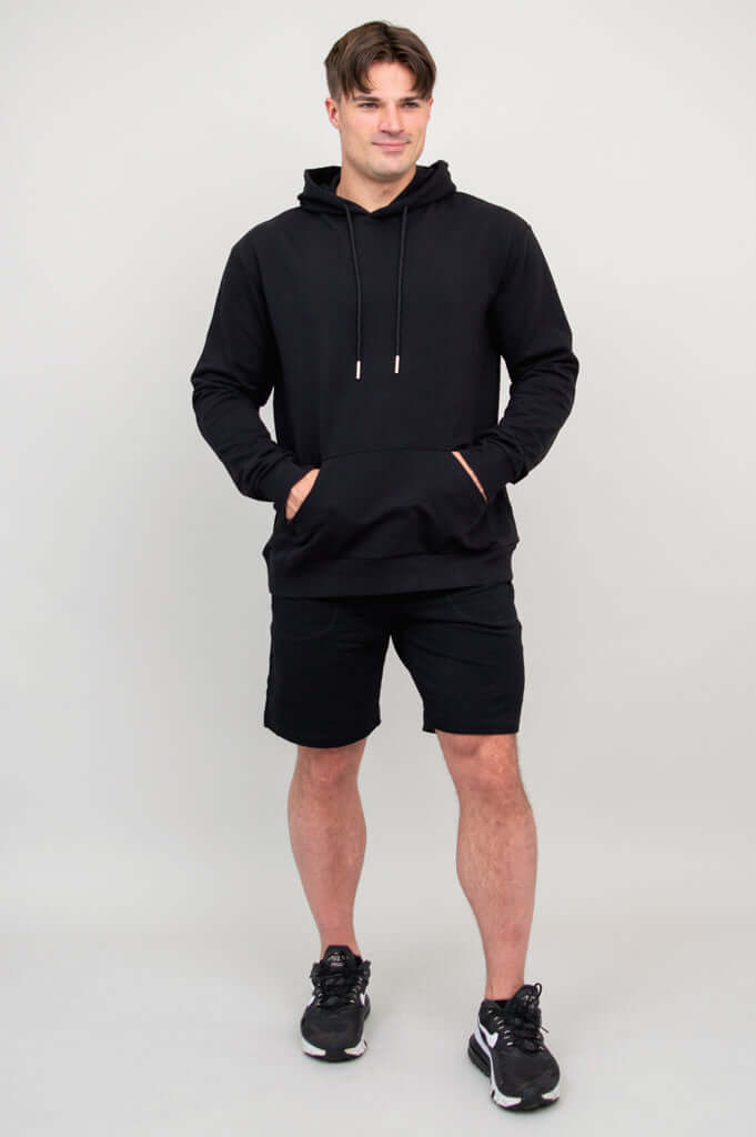 Full body view of man wearing black hoodie and black shorts