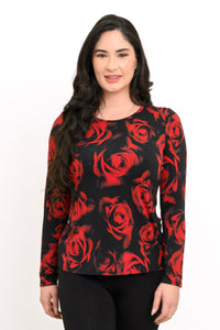 Front view of a female model wearing a long sleeve black top with red roses with black pants, against a white backdrop