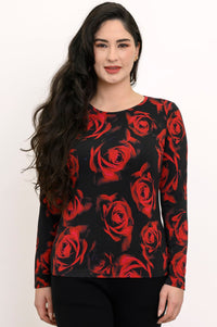 Front view of a female model wearing a long sleeve black top with red roses with black pants, arms at sides, against a white backdrop