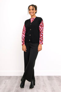 Side-angled view of an onyx knit vest over a pink floral shirt, highlighting the deep ribbed waistband.