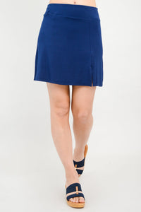 Close up front view of woman wearing a deep blue mini skirt with slit detail and sandals