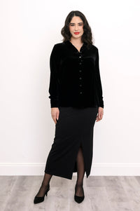 Full-length front view of a woman wearing a black silk velvet button-up shirt and a matching front-slit maxi skirt