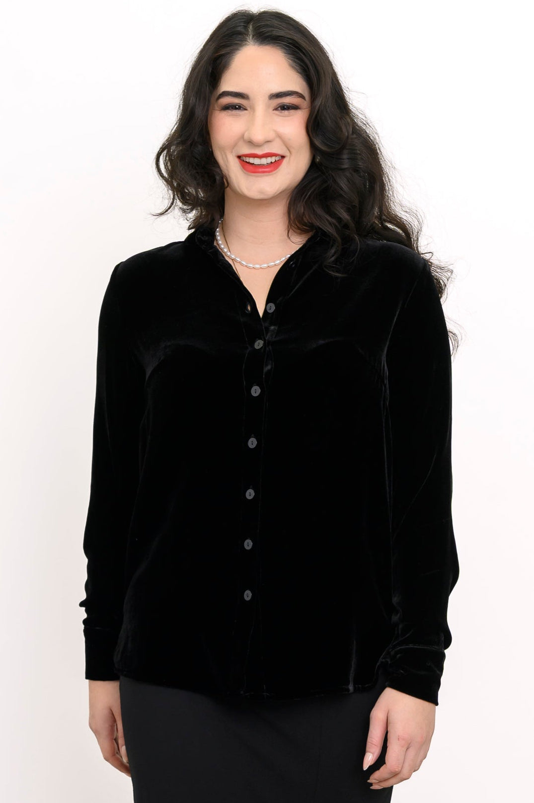 Front view of a smiling woman wearing a black silk velvet button-up shirt with a classic collar