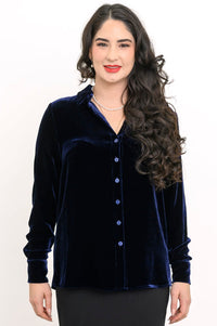 Front view of a smiling woman wearing a navy blue silk velvet button-up shirt with a classic collar