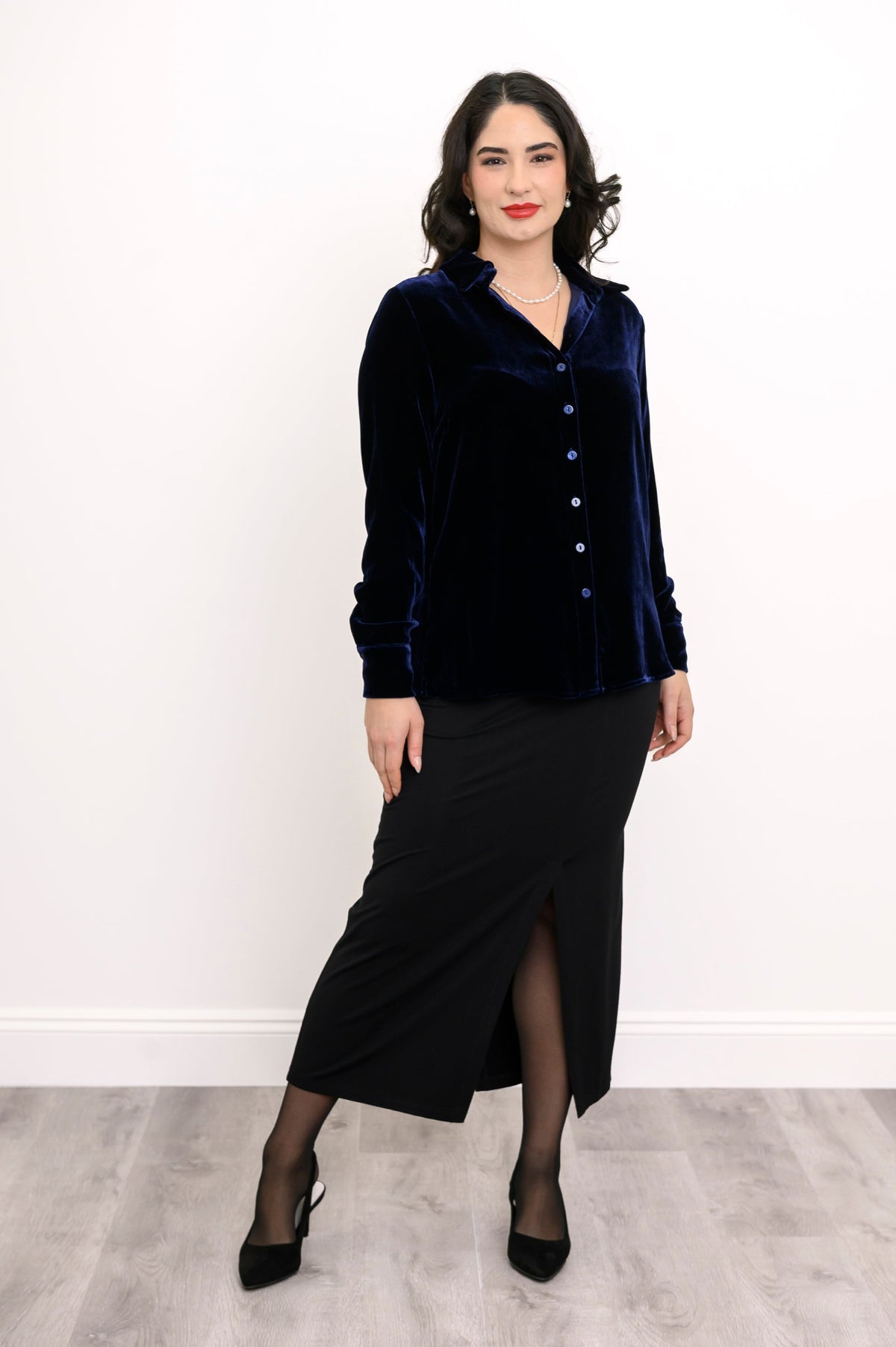 Full-length front view of woman wearing a navy blue silk velvet button-up shirt and a black maxi skirt