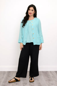 Woman wearing a light blue jacket on a light blue top and black pants on a white background, front view