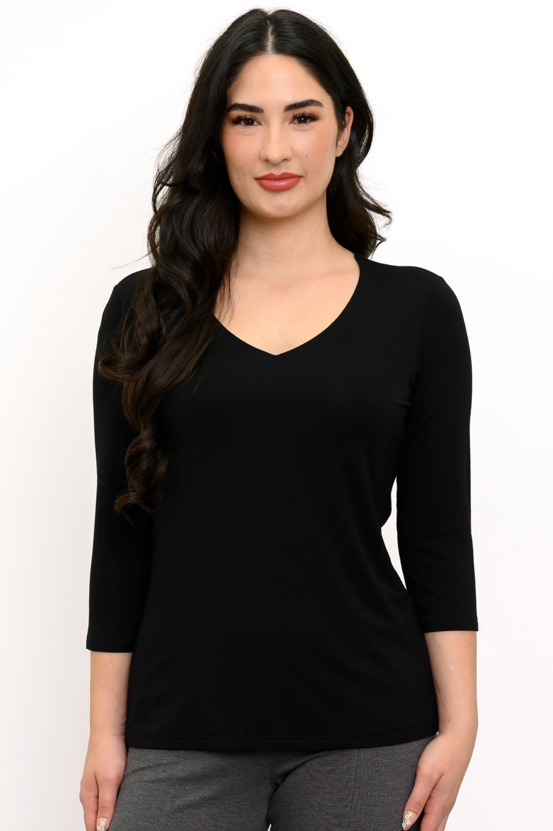 Close up front view of woman wearing a v-neck black top against a white background