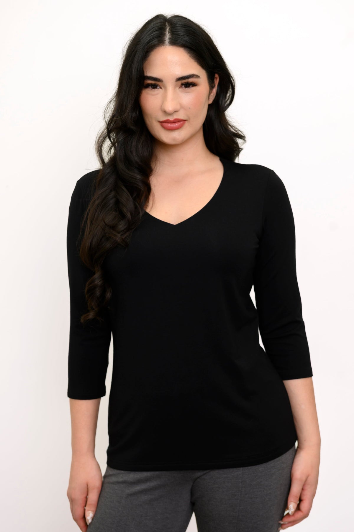 close up front view of woman smiling and and wearing a black 3/4 sleeve top