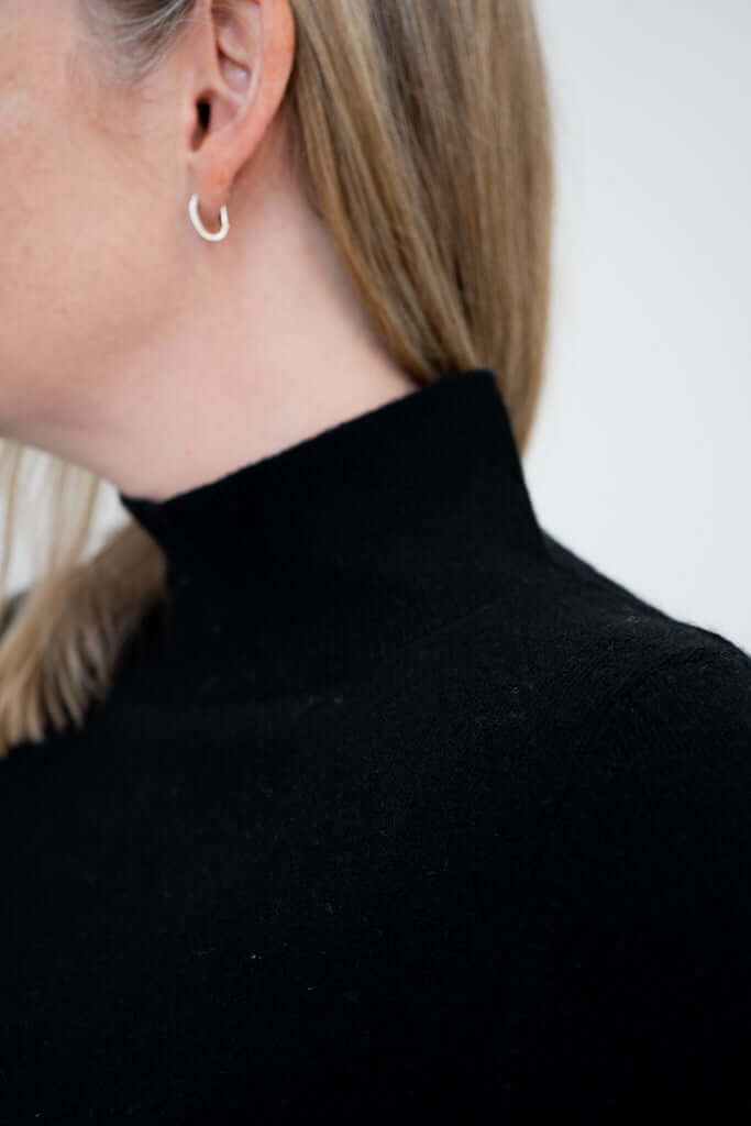 Close-up of black mock neck sweater collar and earring