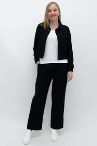 Model wearing black black wide-leg pants with a white top and black jacket, front view