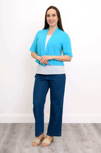 Model with hands clasped, showcasing the blue short-sleeve cropped jacket and jeans
