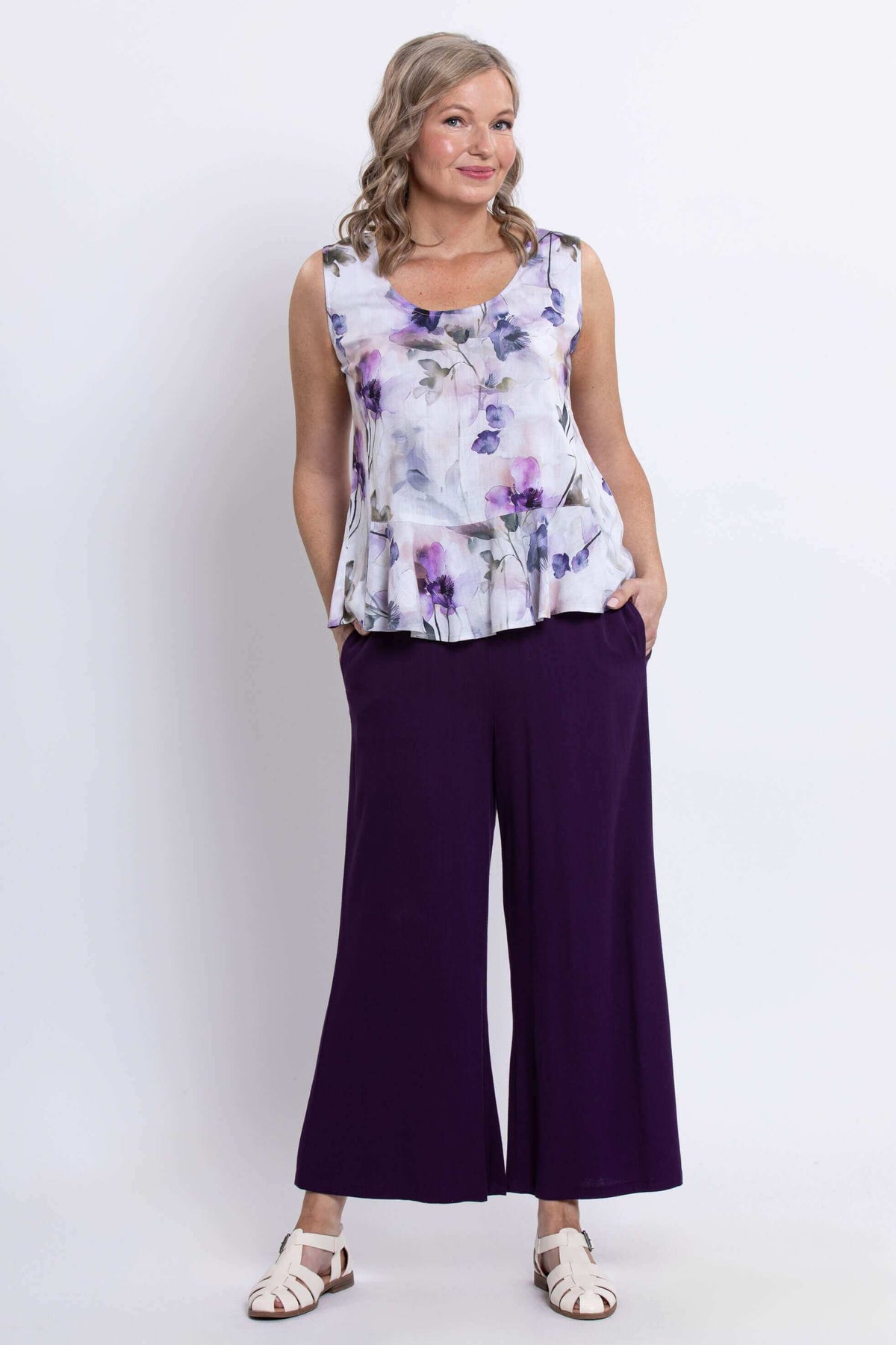 Model in sleeveless top with purple floral pattern paired with wide-leg purple pants