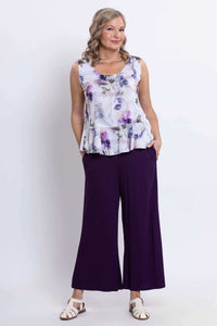 Model in sleeveless top with purple floral pattern paired with wide-leg purple pants