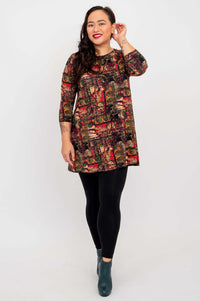 Model posing in Perfect Print A-line tunic with hand raised, wearing black leggings