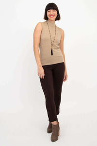 Woman in tan sleeveless sweater smiling with hands at side