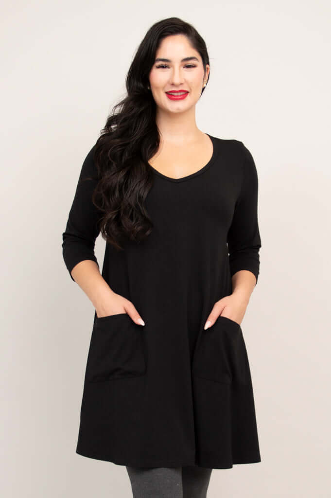 Model wearing black A-line tunic dress with patch pockets and 3/4 sleeves