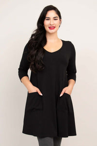 Model wearing black A-line tunic dress with patch pockets and 3/4 sleeves