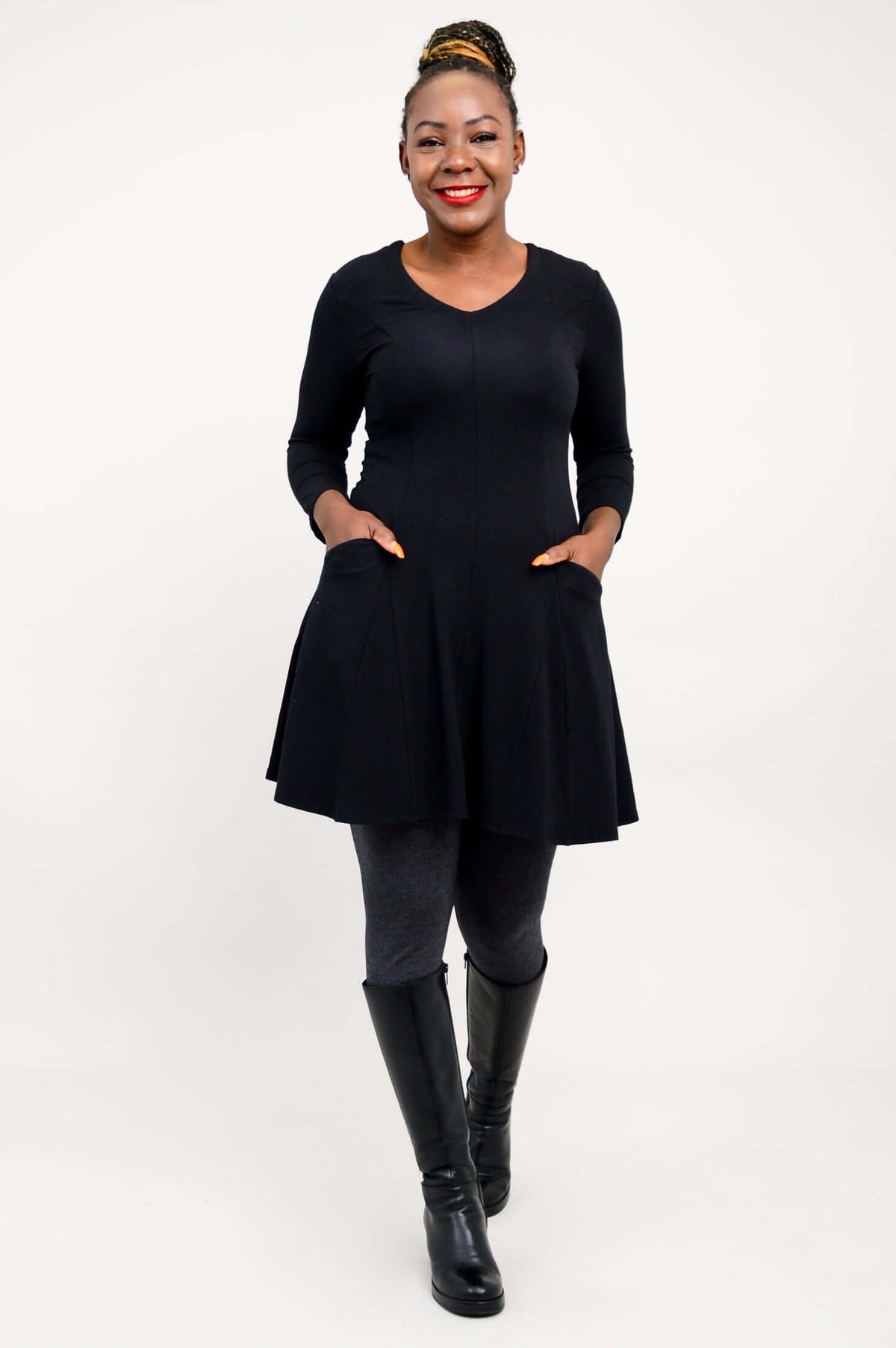 Model in black tunic dress standing with hands in front pockets